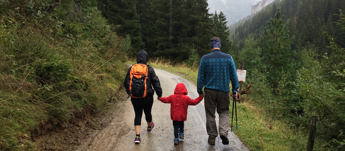 Familie auf Zeit; 3-köpfige Familie geht auf einem Waldweg spazieren